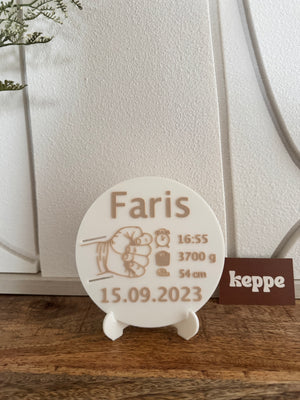 Round white plaque with engraved text of baby's birth date and weight.