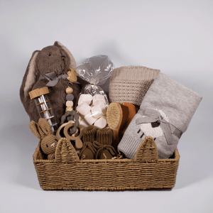 Gift basket with baby items including a plush toy, blanket, and toys on a white background