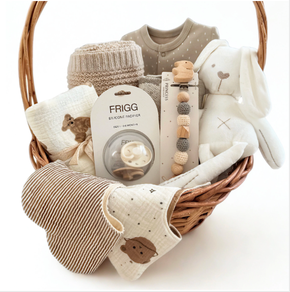 baby gift basket wit plush rabbit, pacifier clip, blanket, onesie, bibs and pacifiers in a woven wooden basket