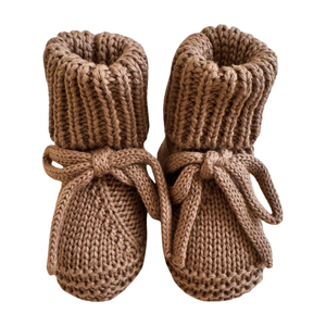 Pair of brown knitted baby booties with ribbons on a white background