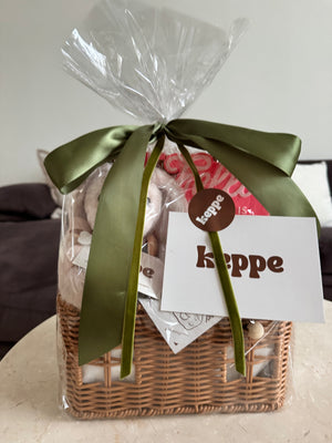 Gift basket with a green ribbon and 'keppe' tag on a neutral background