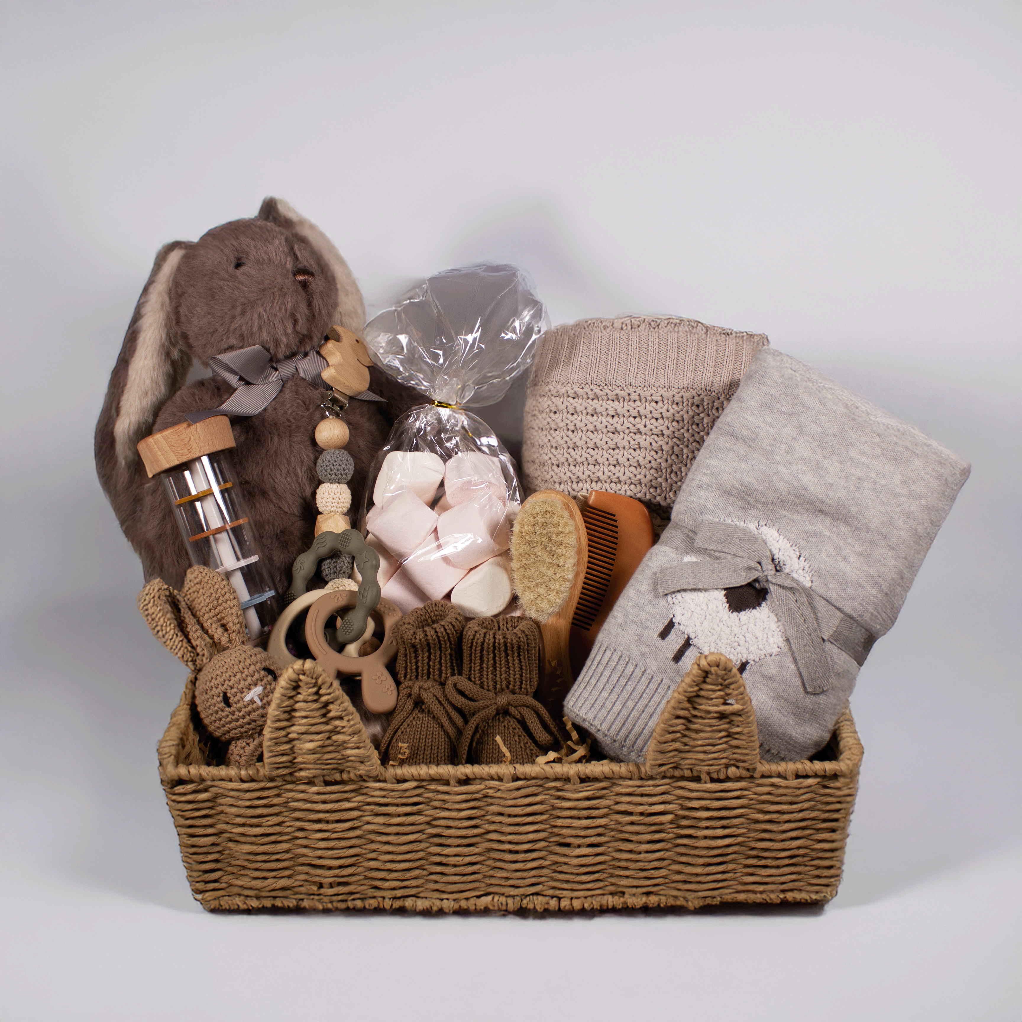 Gift basket with baby items including a plush toy, blanket, and toys on a white background